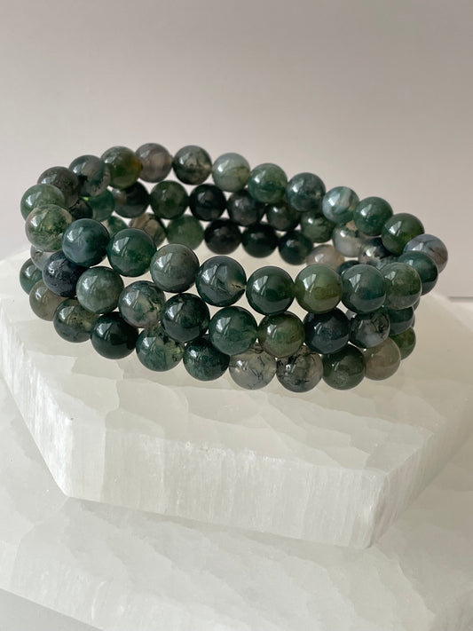 Green Moss Agate bracelets on a white surface.