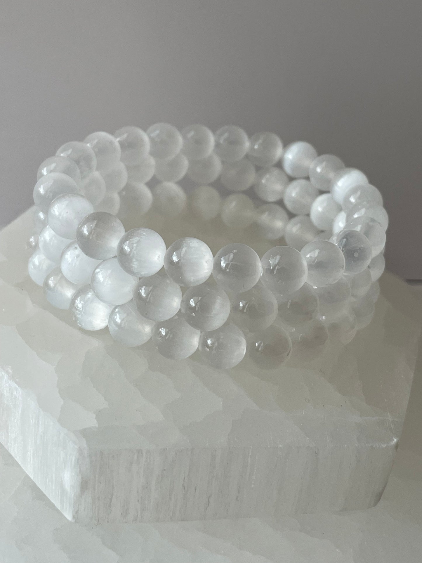 Clear Selenite 8 mm gemstone bracelet placed on a white crystal stone