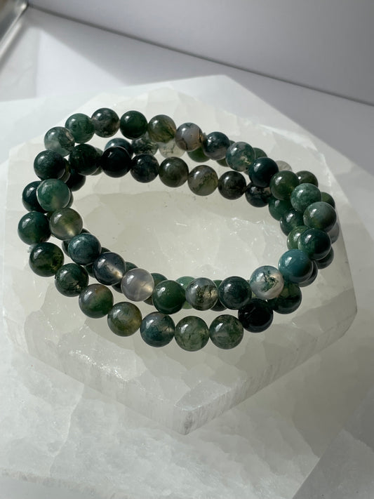 Green Moss Agate bracelet of 8 mm beads placed on a white surface