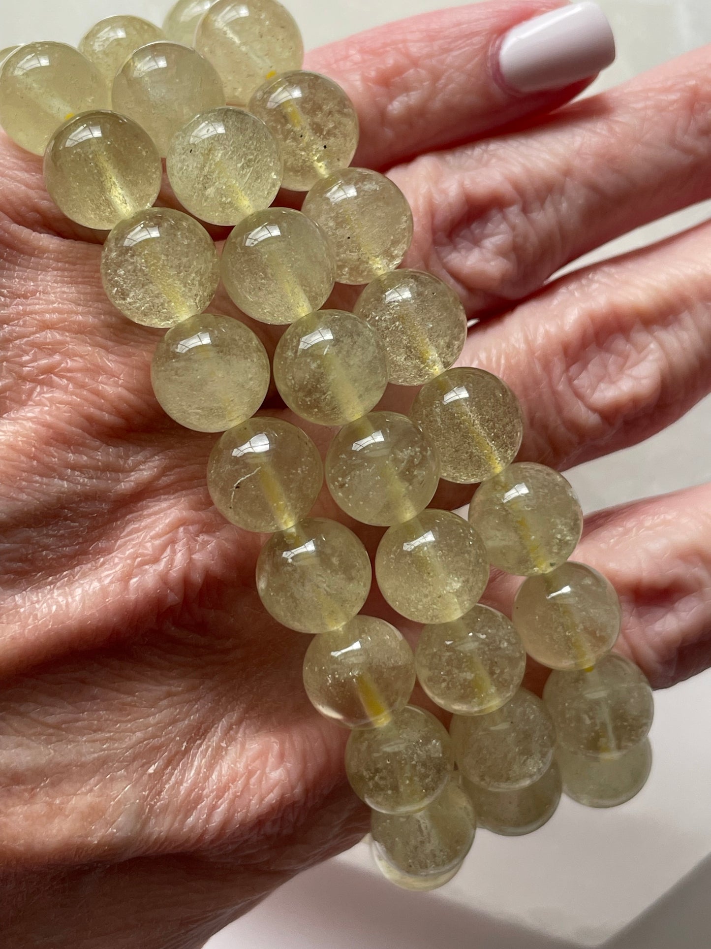 Yellow beaded Libyan Desert Glass bracelet draped across a girl’s finger base.