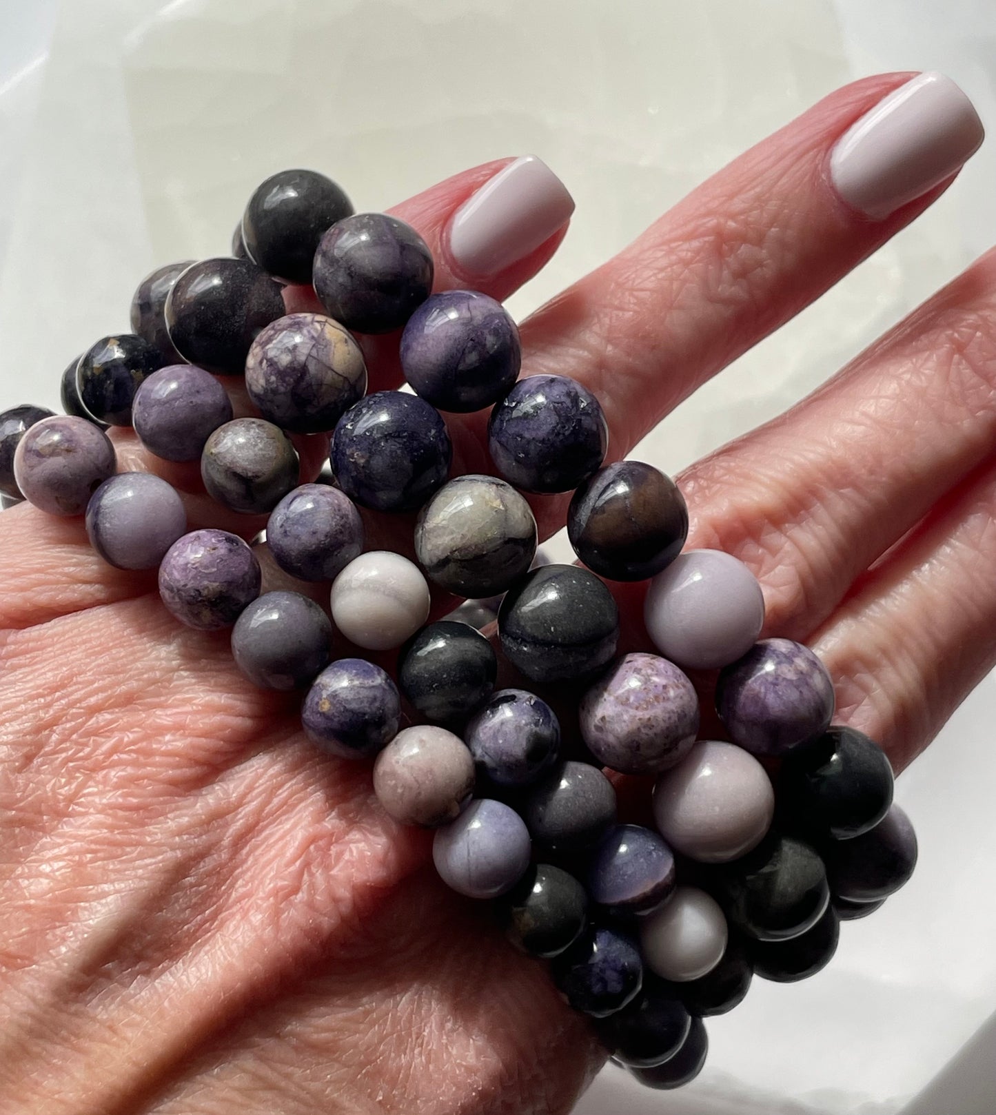 purple Tiffany Stone bracelets worn on female fingers.