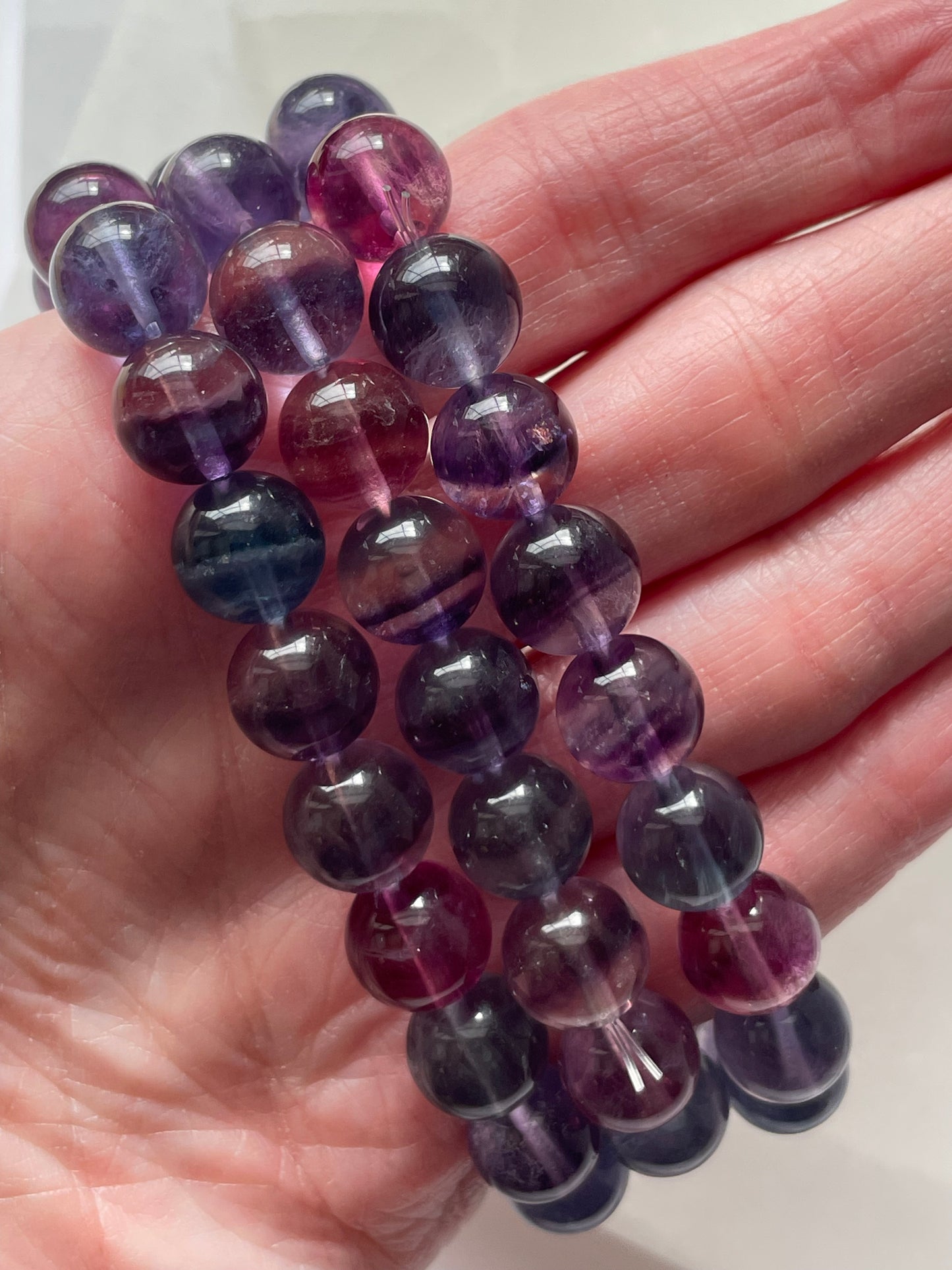 Fluorite gemstone bracelet, 10 mm beads, shown resting on a woman’s knuckles.