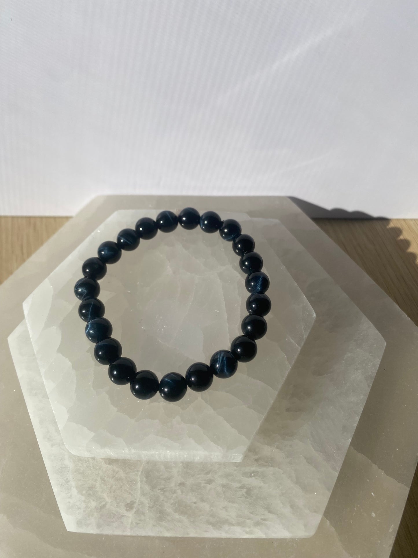 Blue Tiger Eye bracelets on a white geometric display stand.