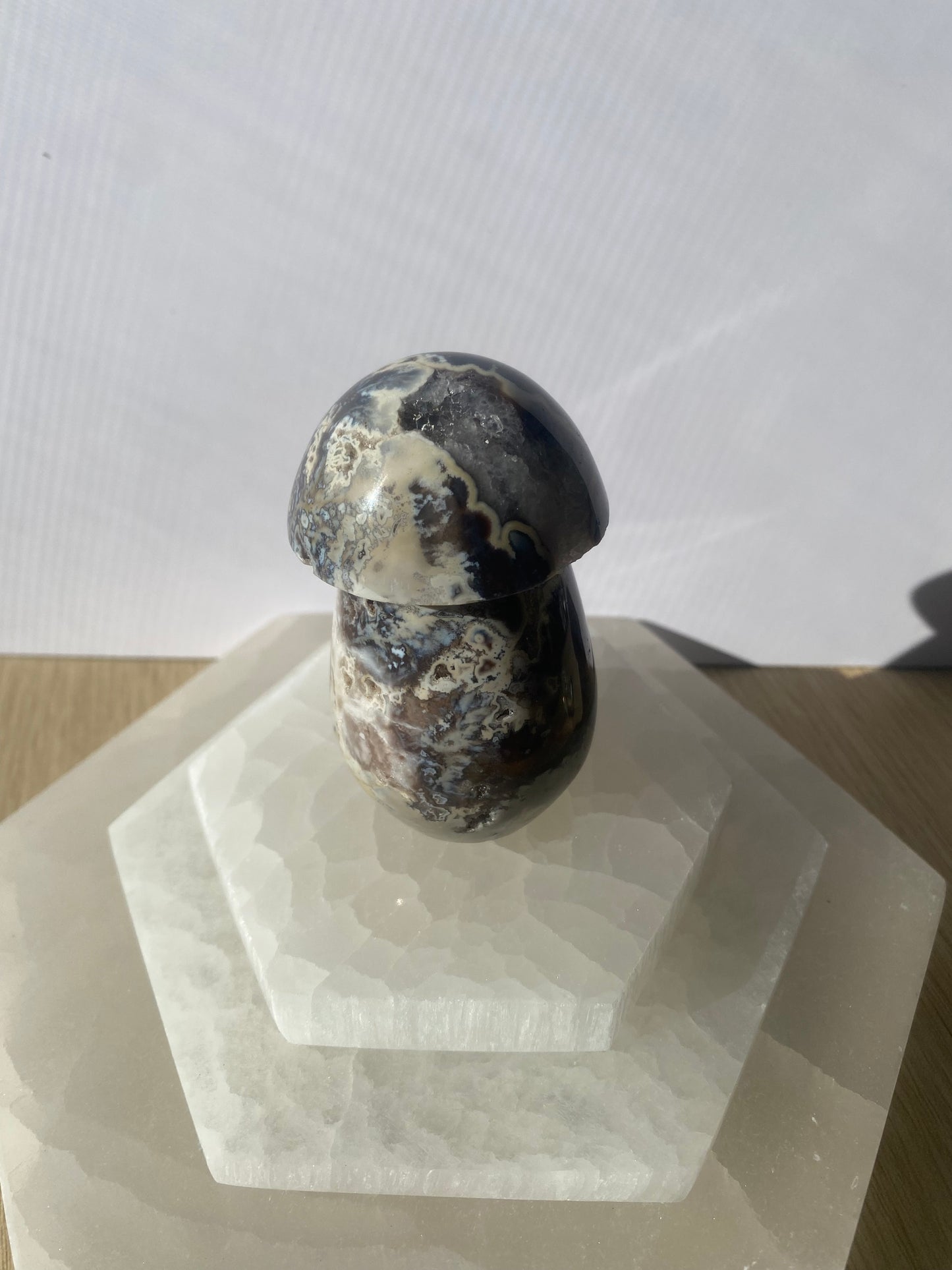 Mushroom-shaped black lotus jasper stone on a clear, geometric stand.