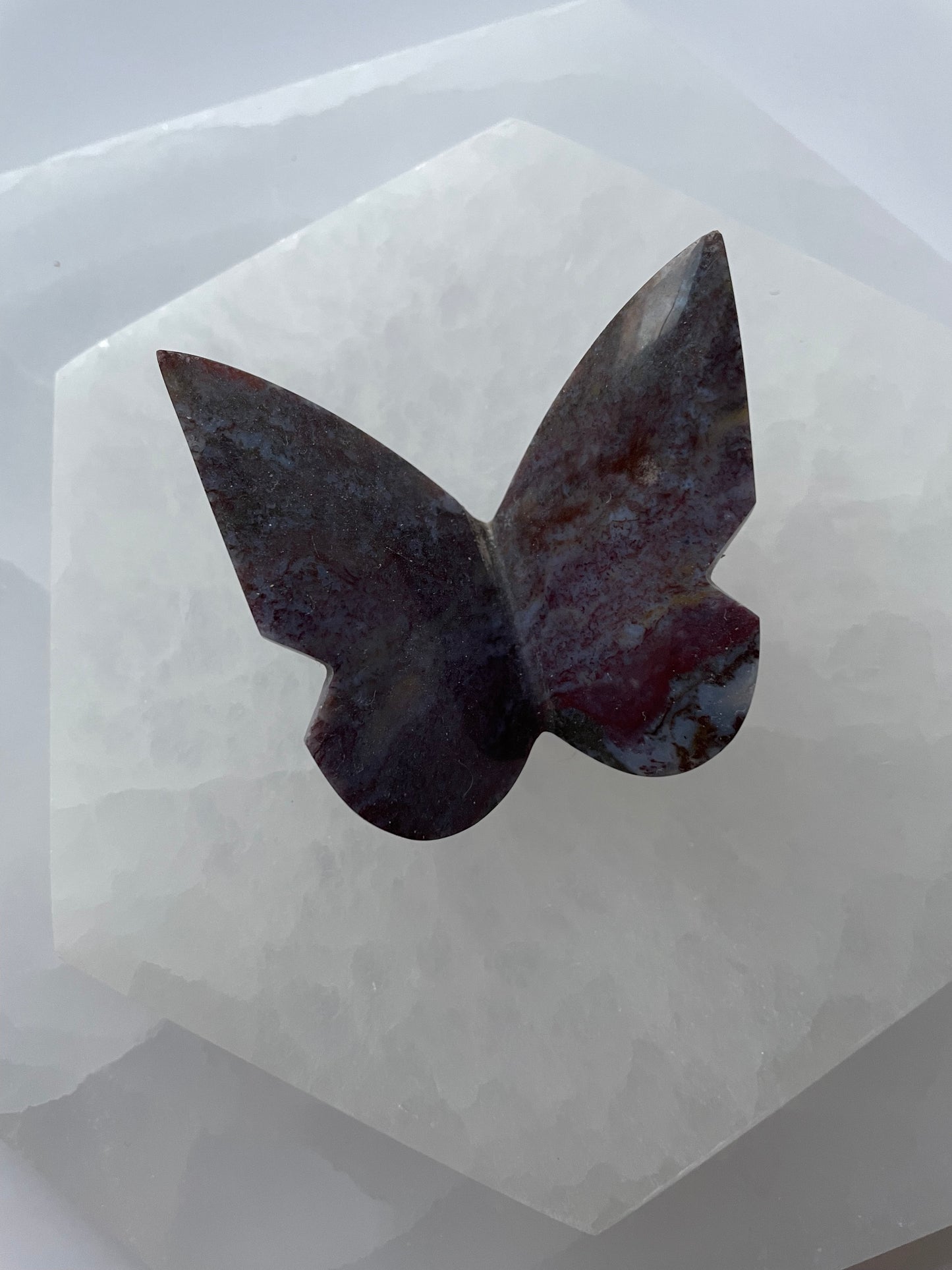 Purple Plume Agate butterfly gemstone displayed on a white surface.