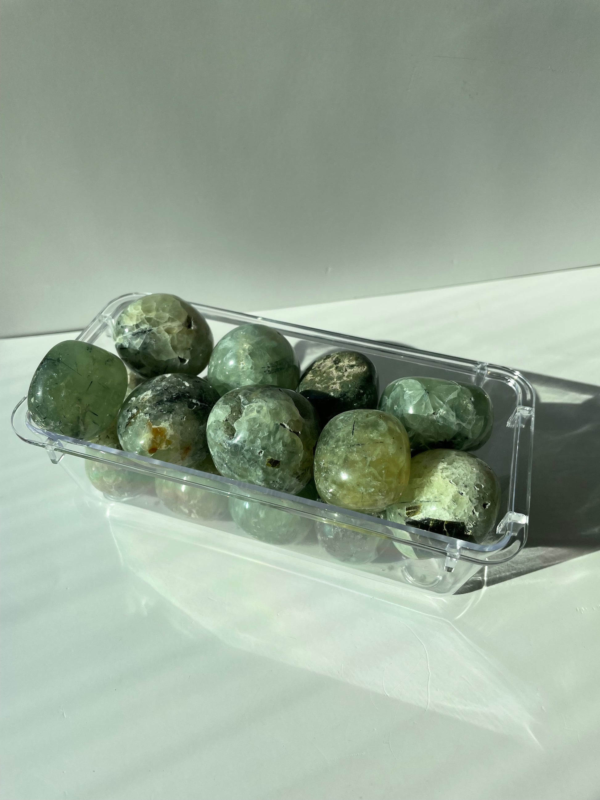 Clear plastic container with green stones on a white background