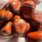 Hand holding a collection of red and orange marbled stones.