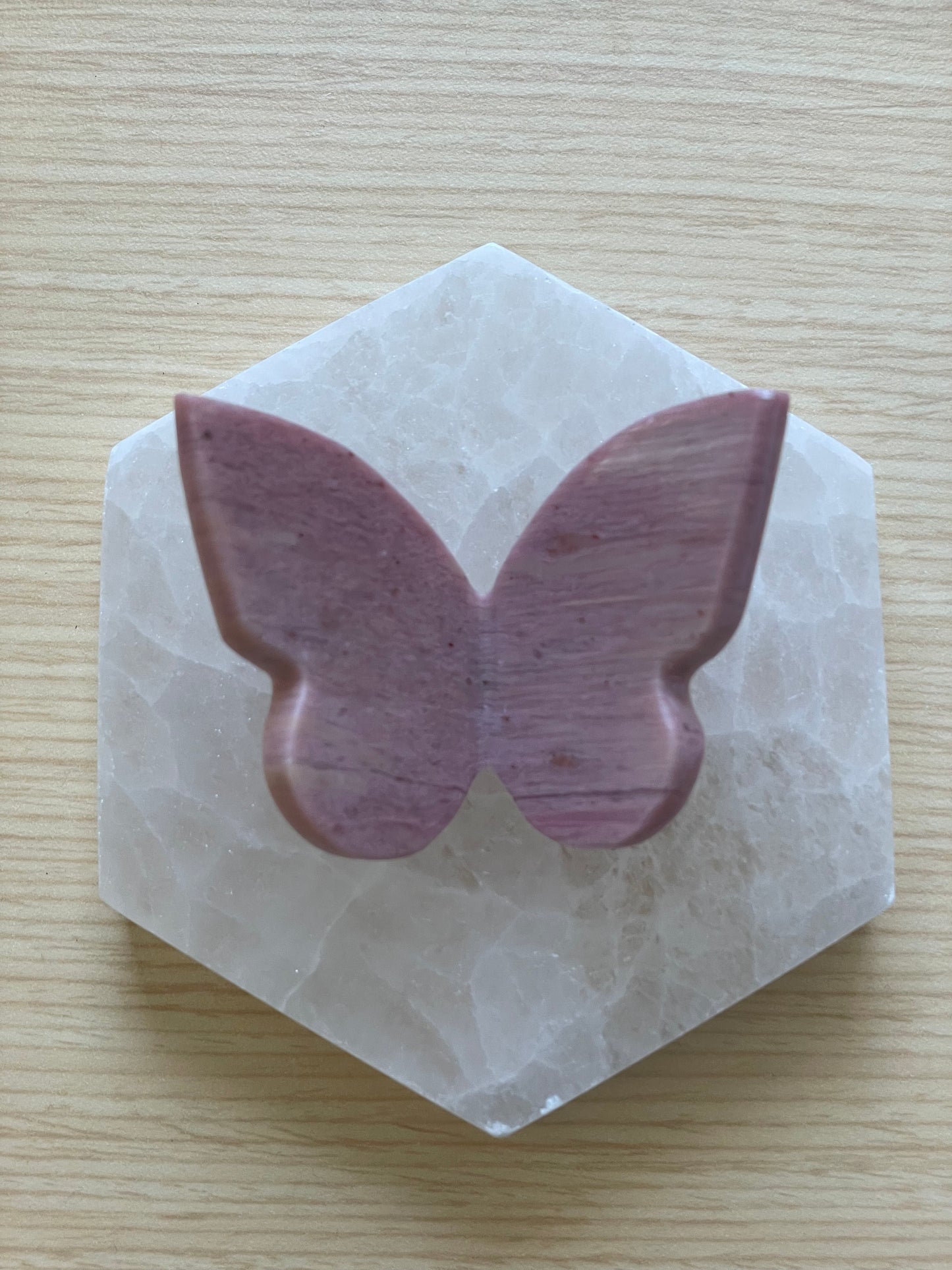 Decorative pink petrified wood butterfly resting on hexagonal stone.