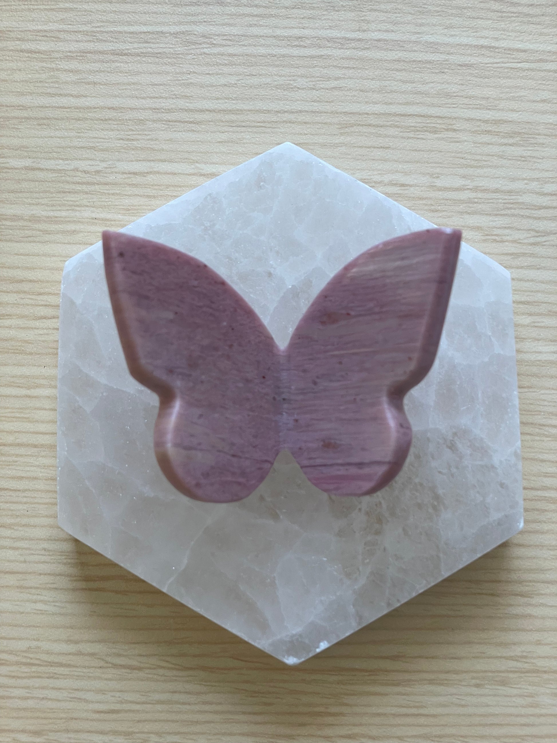 Decorative pink petrified wood butterfly resting on hexagonal stone.