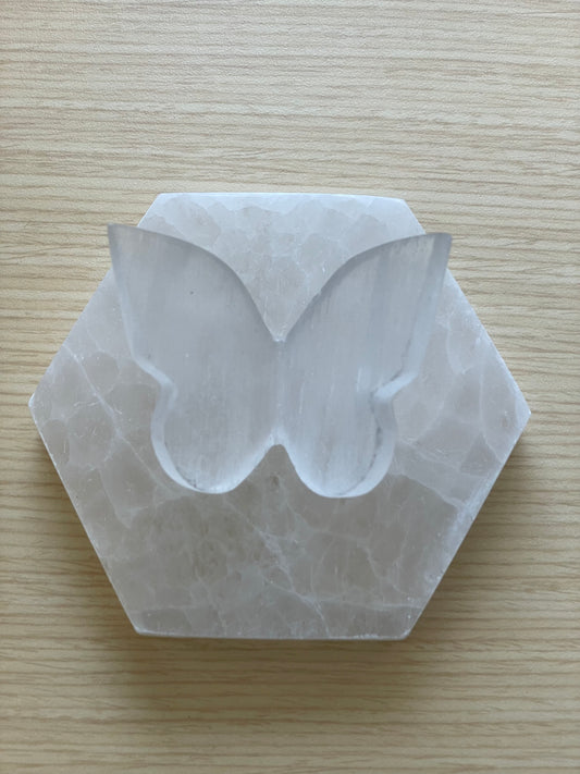 Selenite butterfly on a Hexagonal stone on a wooden surface