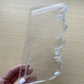 Selenite slab held by a hand on a wooden surface.