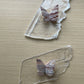 Two clear acrylic stands with butterfly specimens on a beige surface