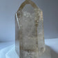 Large smoky quartz tower on white surface.